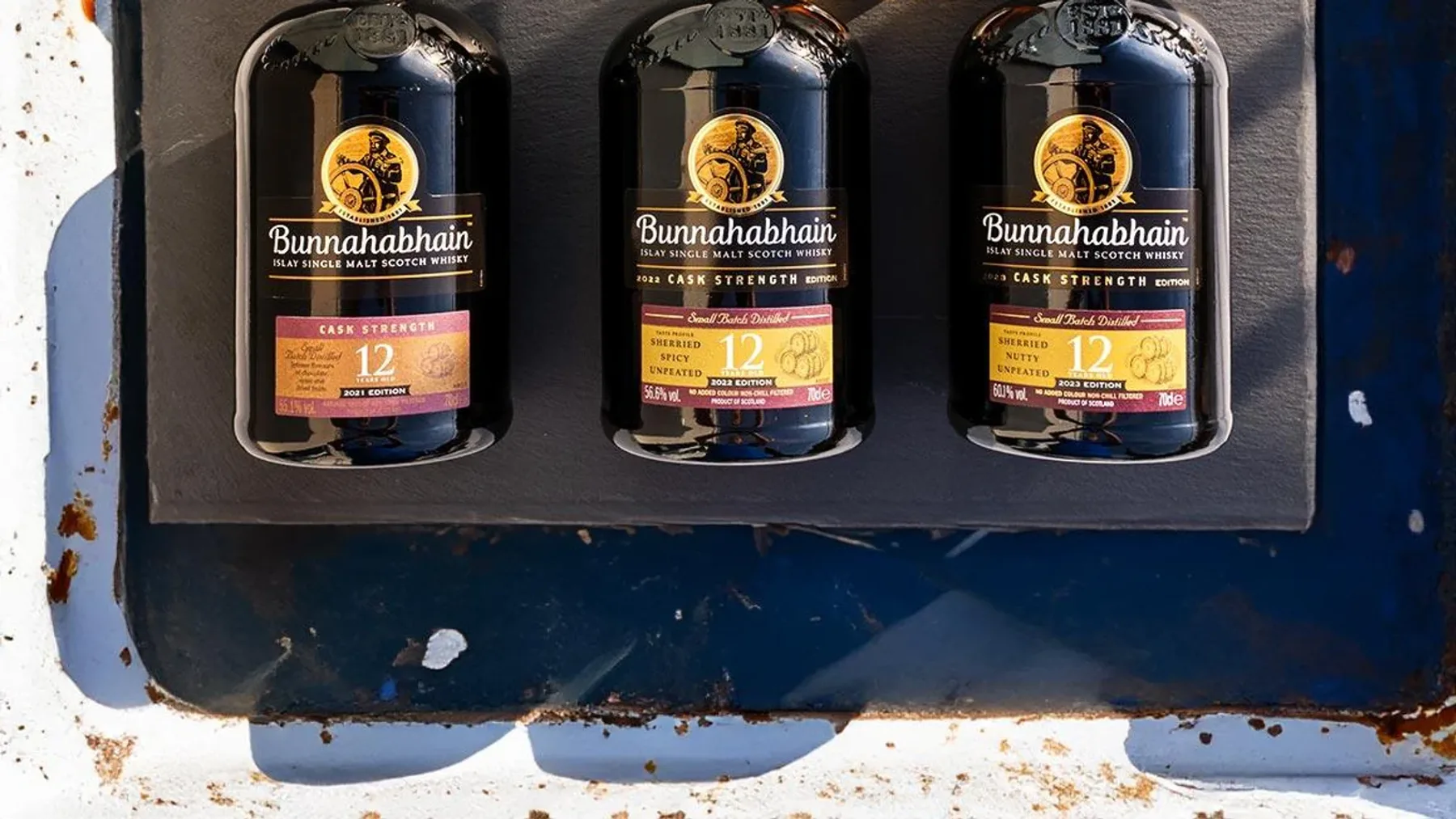 Bunnahabhain 12 Cask Strength 2023 viski şişesi ve tadım kadehi masada yan yana duruyor.
