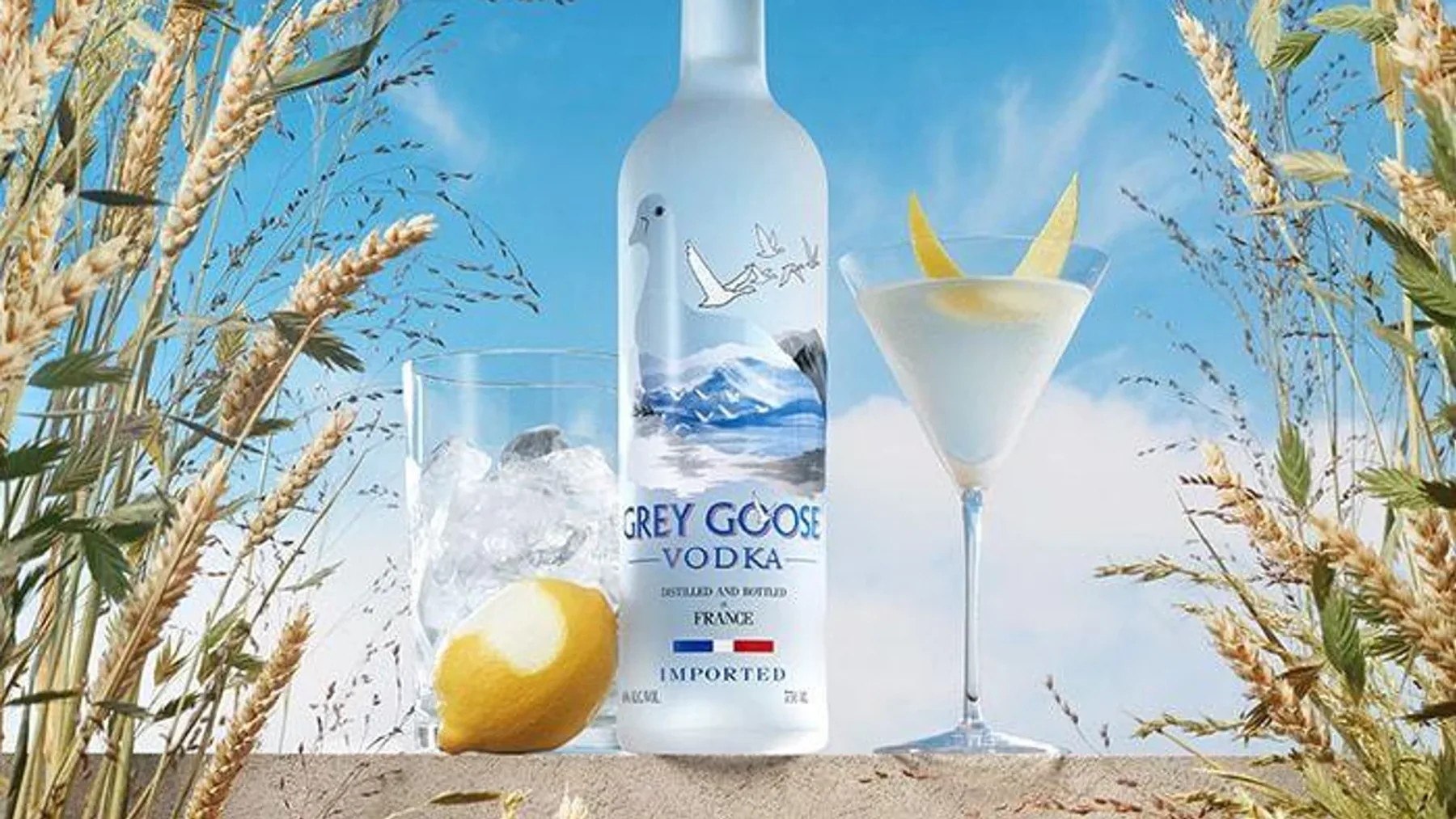 Uçan kaz motifleri ve dağ gölü manzaralı uzun ince şeffaf bir Grey Goose votka şişesi