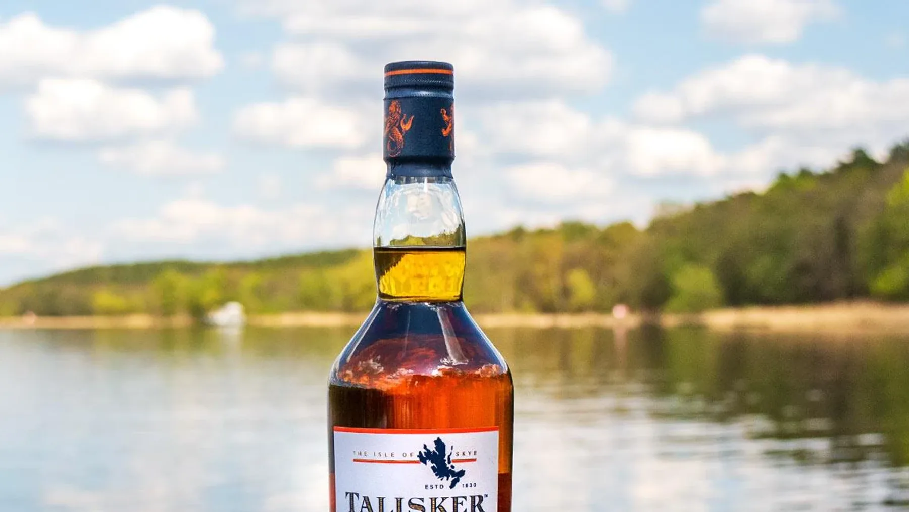 Loch Harport kıyısında yer alan tarihi taş damıtımevi binası önünde duran bir şişe Talisker 10 yıllık viski