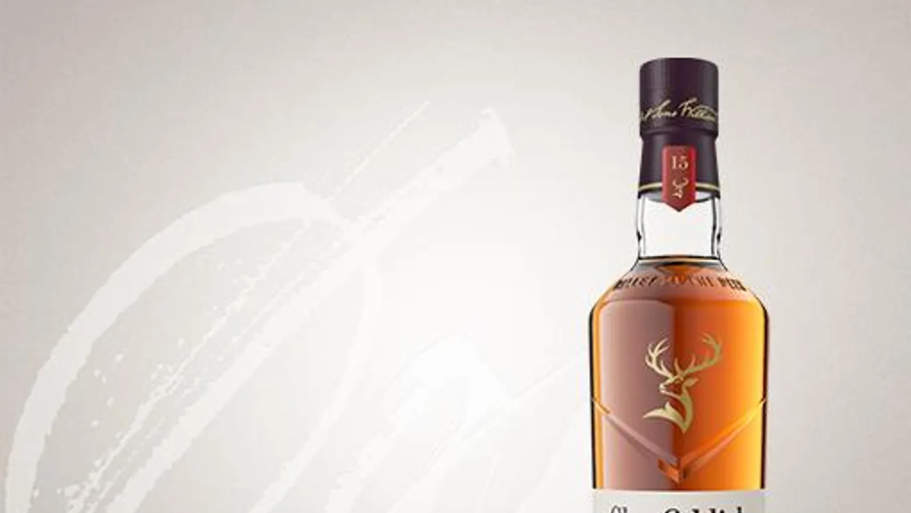 Beyaz camdan yapılmış üçgen tasarımlı Glenfiddich 15 viski şişesi ve mor renkli hediye kutusu yan yana duruyor