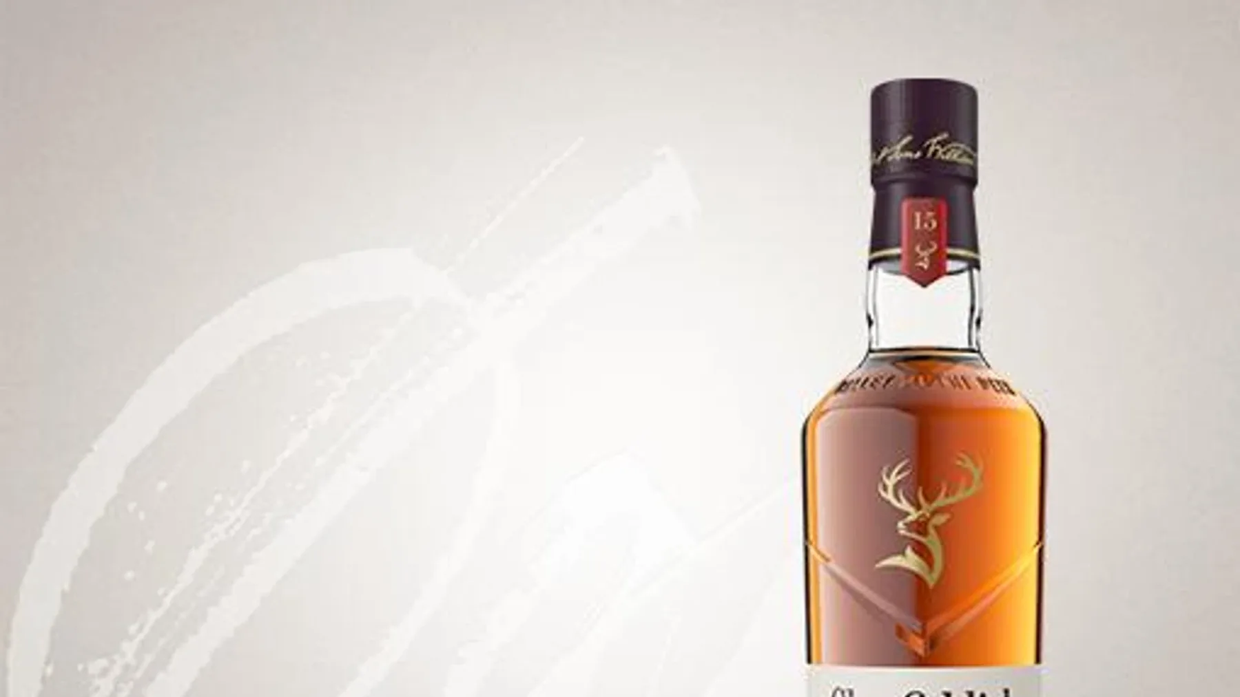Beyaz camdan yapılmış üçgen tasarımlı Glenfiddich 15 viski şişesi ve mor renkli hediye kutusu yan yana duruyor