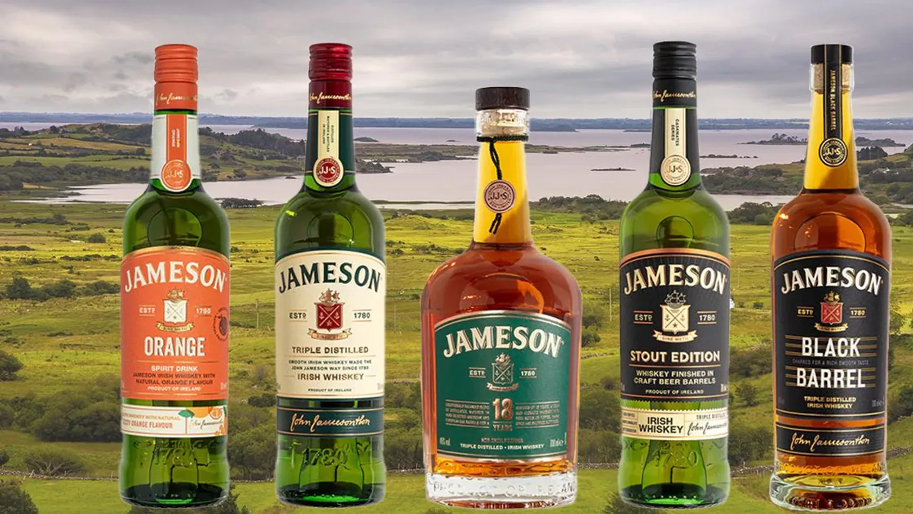 County Cork'taki Midleton Damıtım Evi'nde meşe fıçıların önünde duran üçlü damıtılmış Jameson viski şişesi